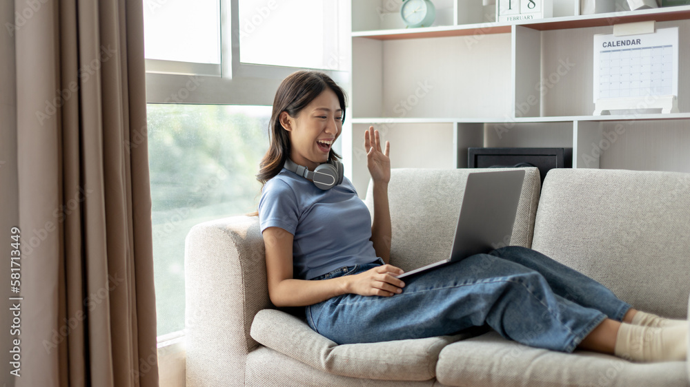 Fototapeta premium Young Asian woman greets his friends and teachers in a live video with a smile on his face, Online communication , Stay home, New normal, VDO Call, Social distancing, Internet learning.