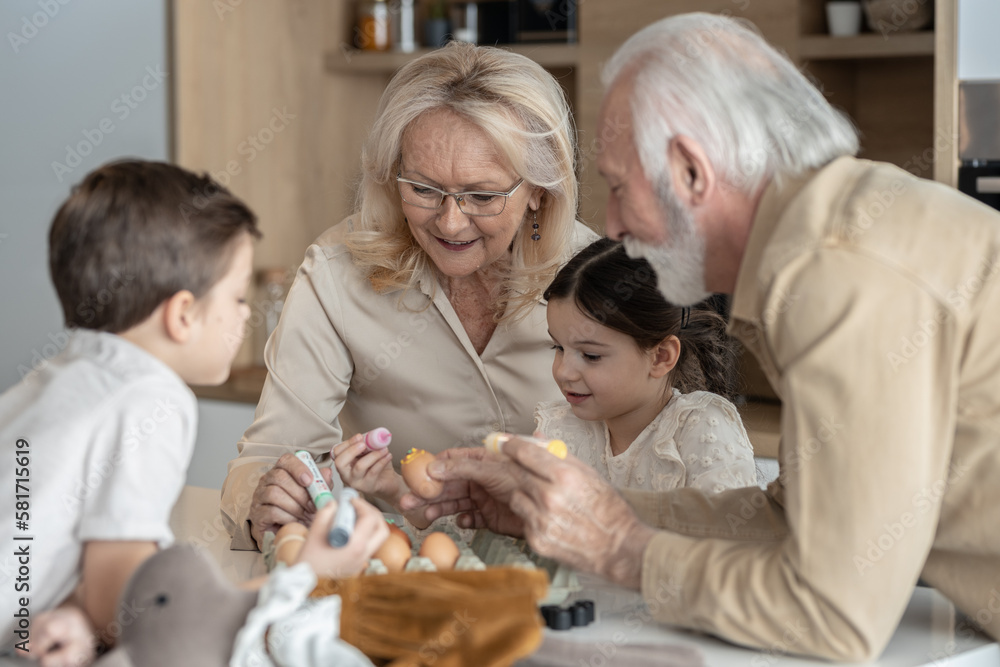 Brother and sister decorating Easter eggs with their grandparents