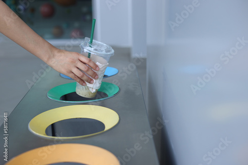 Woman hand holding throwing plastic cup in litter bin