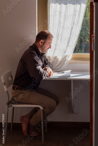  man sits on a chair at a table and reads a book