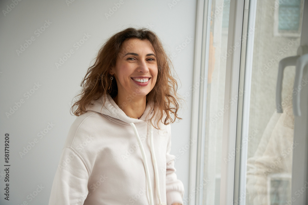 Portrait of happy smiling female relaxing at home looking straight into the camera. Attractive brunette caucasian girl with curly hair. Portrait of happy smiling female relaxing at home looking straight into the camera. Attractive brunette caucasian girl with curly hair.