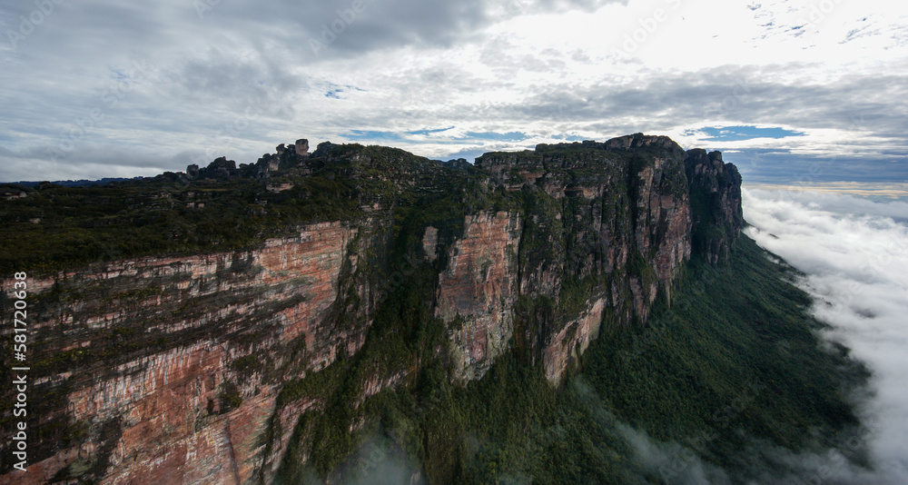 Towering sandstone rock cliffs of Auyan Tepui in the morning light with clouds on the lower slopes, Venezuela