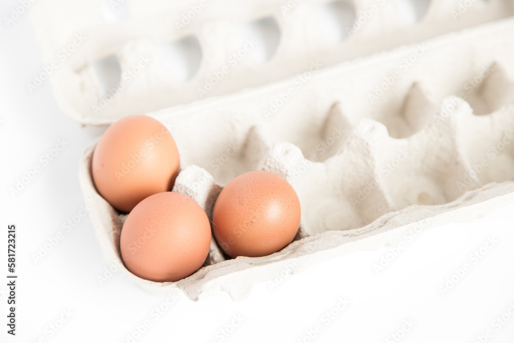 Detail of an open recycled cardboard egg carton with some eggs inside on a white background with copy space. Detail of an open recycled cardboard egg carton with some eggs inside on a white background with copy space.