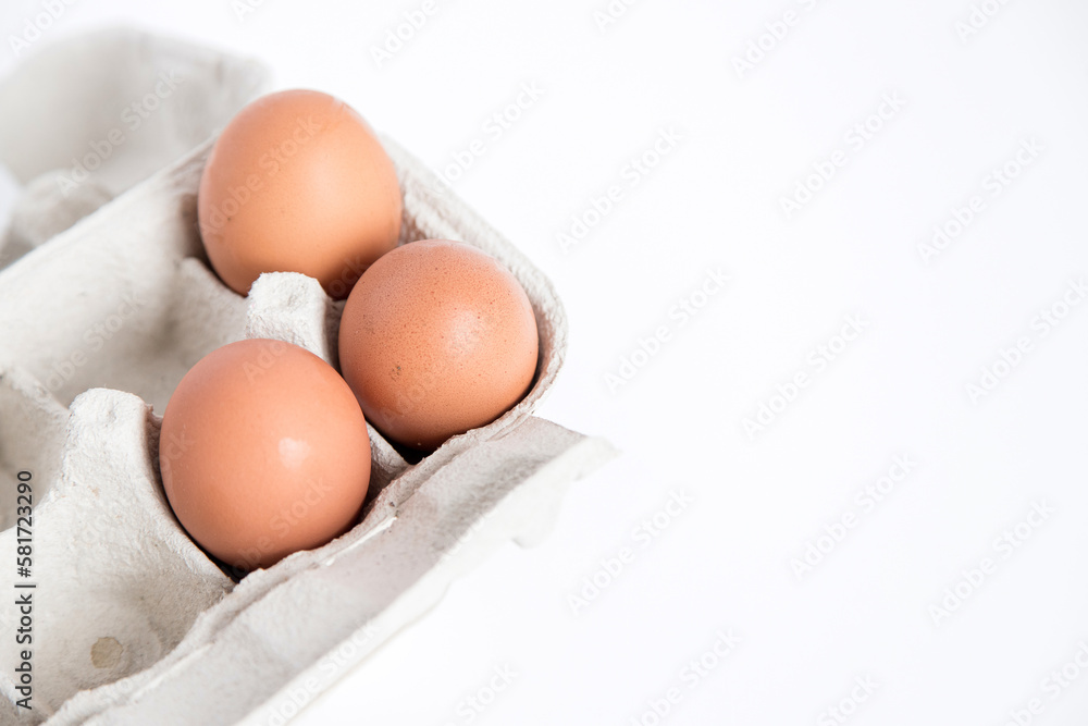 Detail of an open recycled cardboard egg carton with some eggs inside on a white background with copy space.