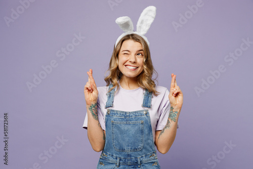 Foto Young woman wearing casual clothes bunny rabbit ears waiting for special moment, keeping fingers crossed, making wish isolated on plain pastel light purple background