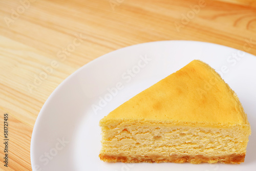 A slice of delicious baked cheesecake on white plate