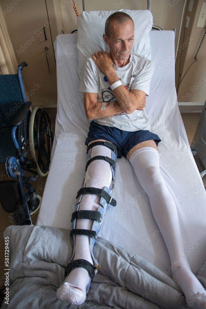 a man with a broken leg in an orthese in bed in a clinic after an accident,  Stock-Foto | Adobe Stock