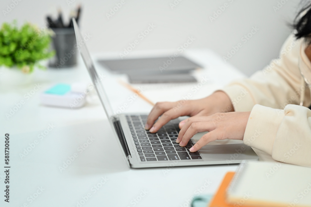 Close up view of female employee hands typing on laptop compute keyboard, searching online information working at office desk Close up view of female employee hands typing on laptop compute keyboard, searching online information working at office desk