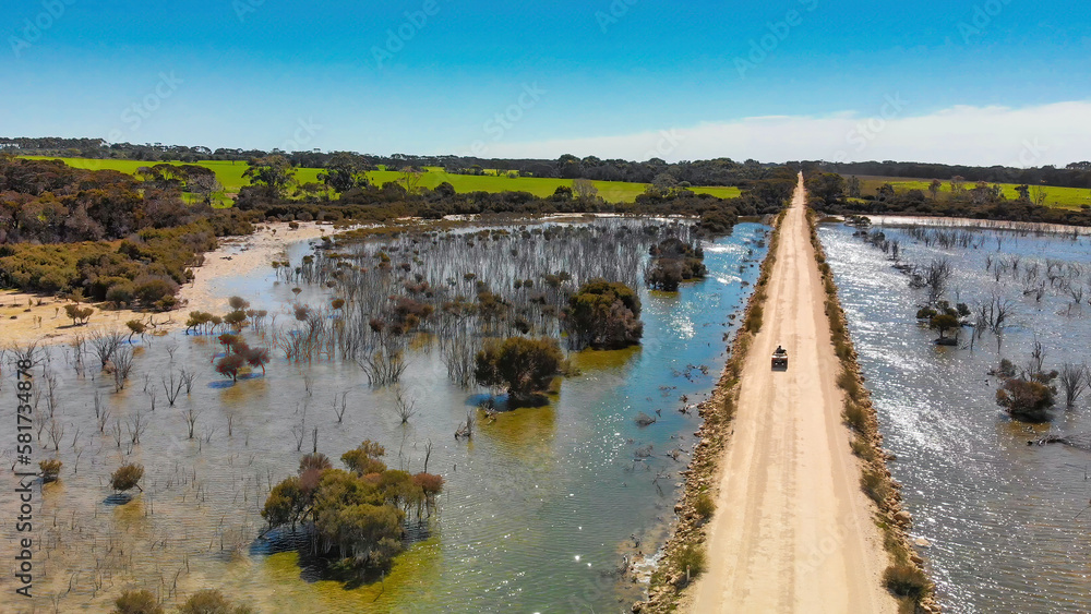 Kangaroo Island unpaved road along lake and trees, aerial view from drone - Australia