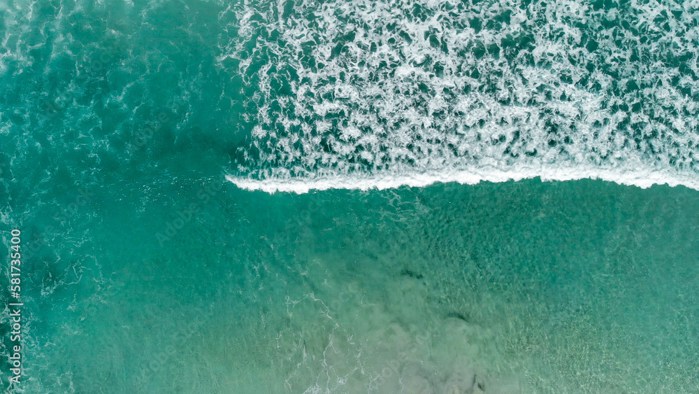 Above the ocean, aerial view at the waves and surface near shoreline - Drone viewpoint