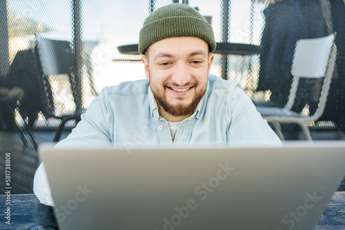 Young handsome man sitting in cafe, typing and using laptop. Handsome hipster using computer at cafe.