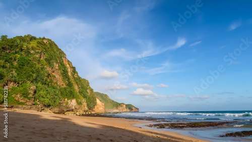 Fototapeta Naklejka Na Ścianę i Meble -  Tropical rocky beach with white sand and cliffs and blue sky with clouds on Sunny day. Summer tropical landscape, panoramic view. travel tourism wide panorama background concept. 
