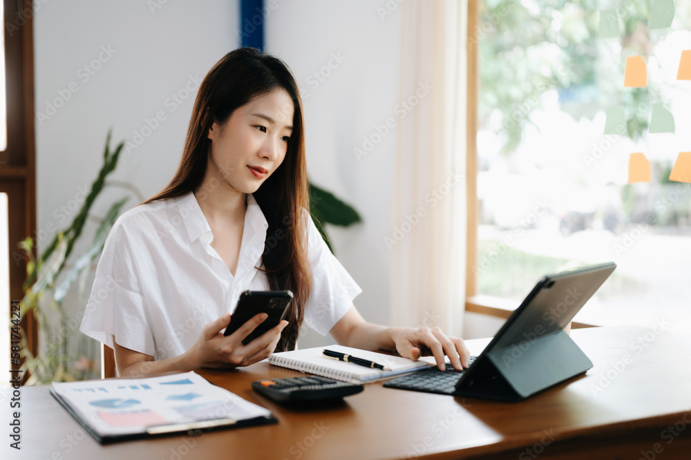 Asian woman working in the office with working notepad, tablet and laptop documents Asian woman working in the office with working notepad, tablet and laptop documents