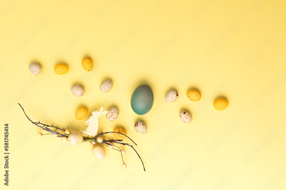 Obraz premium Colored eggs of different sizes on a yellow background. Symbol of the Easter holiday. Easter background. Flat lay