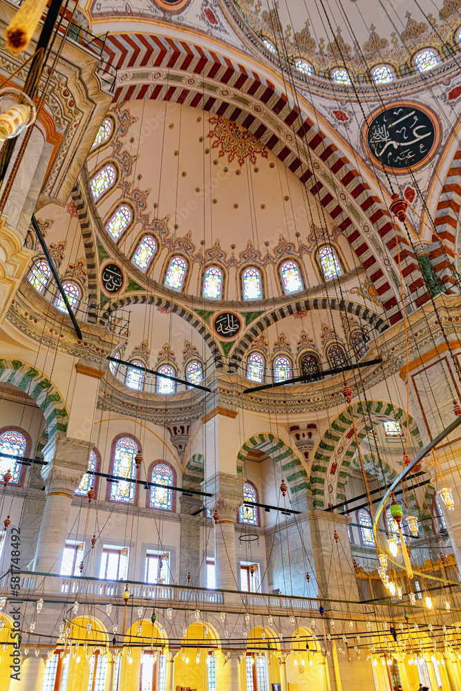 Interior of Fatih Mosque, Ottoman mosque in the Fatih district of Istanbul, with a huge decorated domes. Arabic text as decor (verses from Koran, muslim Holy book). Istanbul, Turkey