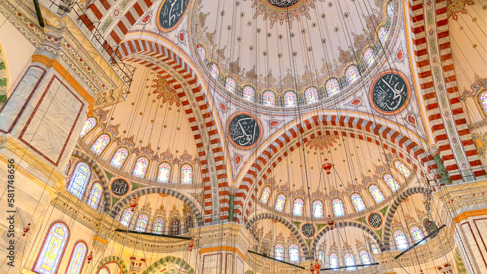 Interior of Fatih Mosque, Ottoman mosque in the Fatih district of Istanbul, with a huge decorated domes. Arabic text as decor (verses from Koran, muslim Holy book). Istanbul, Turkey
