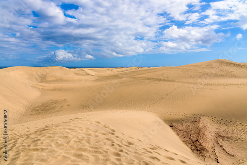 View of desert sand dunes against a moody cloudy blue sky. Maspalomas Dunes in Playa del Ingles  Maspalomas  Gran Canaria  Spain.