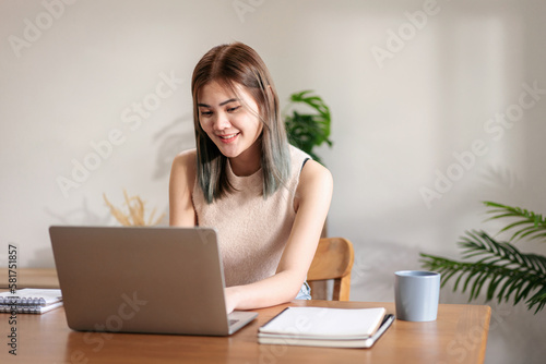 Female fashion artist working and typing data on laptop while th