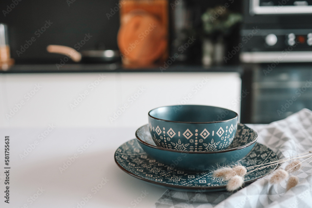 Set of stylish dishes with an ornament on the table against the backdrop of the kitchen