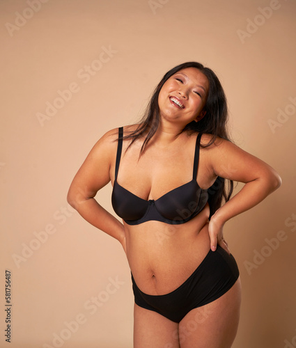 Full length of cheerful Chinese woman wearing underwear in studio shot