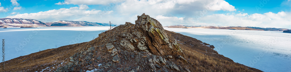 Fototapeta premium BAIKAL LAKE,RUSSIA-MARCH 1,2023:Panoramic wiew of the winter Baikal through the mountain.