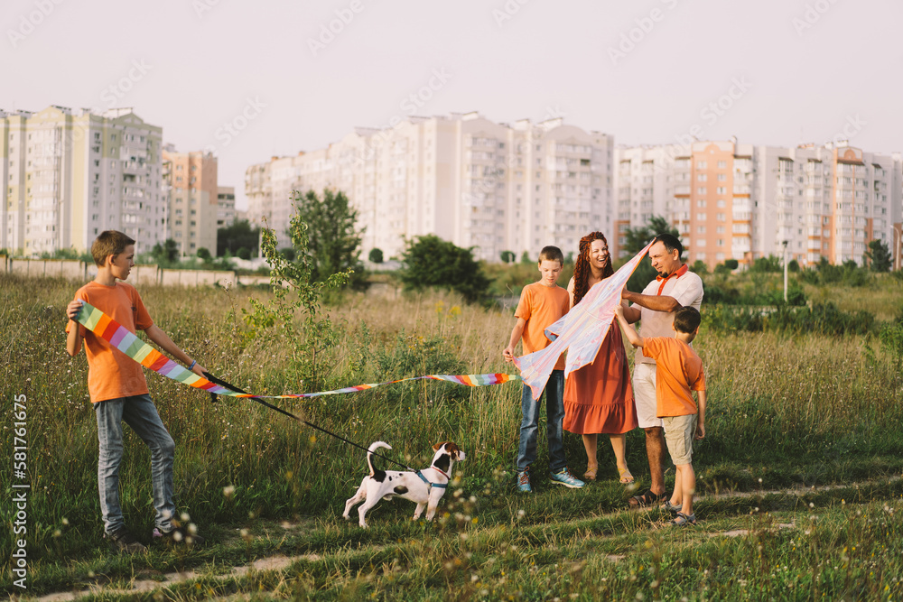 Happy family and children run on meadow with a kite in the summer on the nature. Family playing with kite while running along rural summer field. Family day Happy family and children run on meadow with a kite in the summer on the nature. Family playing with kite while running along rural summer field. Family day