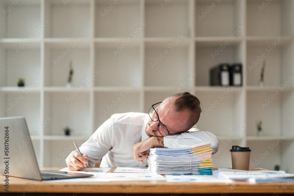 Business man sad tired exhausted frustrated sick ill sleepy employee business man in sit work at office desk with laptop sleep put head on table Business man sad tired exhausted frustrated sick ill sleepy employee business man in sit work at office desk with laptop sleep put head on table