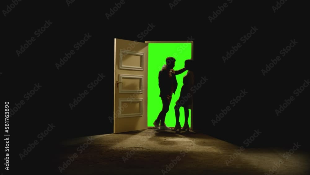 Side view of couple standing opposite and looking each other in front of an open door with darkness behind . Footage of couple stand on floor near door with green screen .  Concept of dream or romance