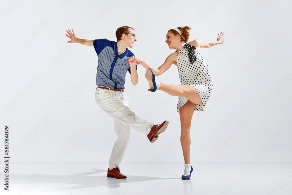Happy and delightful people. Young man and woman in stylish clothes dancing retro dance against grey studio background. Concept of art, retro style, hobby, party, fun, movements, 60s, 70s culture Happy and delightful people. Young man and woman in stylish clothes dancing retro dance against grey studio background. Concept of art, retro style, hobby, party, fun, movements, 60s, 70s culture