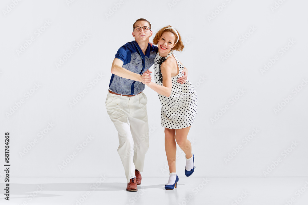 Young happy man and beautiful smiling woman in stylish clothes dancing retro dance against grey studio background. Concept of art, retro style, hobby, party, fun, movements, 60s, 70s culture Young happy man and beautiful smiling woman in stylish clothes dancing retro dance against grey studio background. Concept of art, retro style, hobby, party, fun, movements, 60s, 70s culture