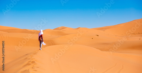 Young beautiful caucasian woman posing with white textile flying in the sahara desert in Morocco