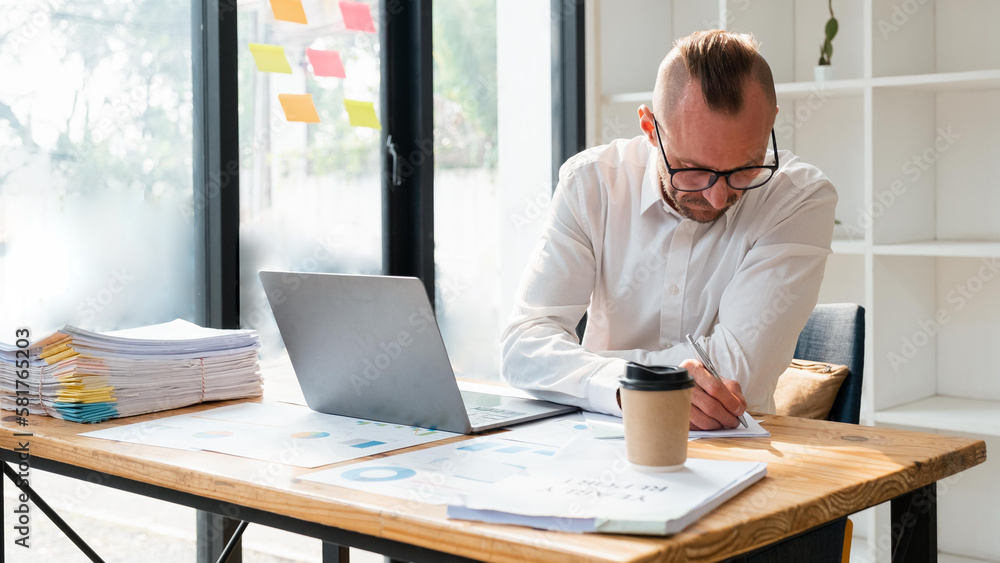 business man in casual making notes in notepad while sitting in his office business man in casual making notes in notepad while sitting in his office