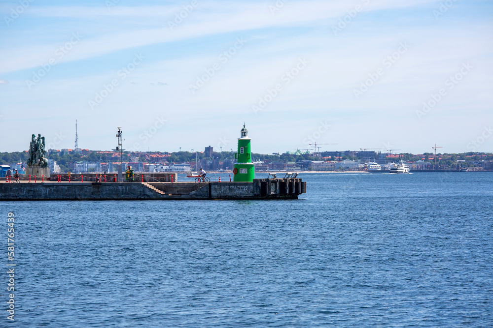 Green lighthouse on the breakwater in front of the port basin, a berth for ships, Helsingor, Denmark