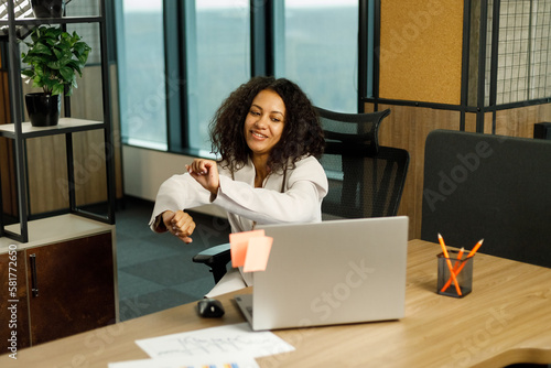 Joyful african american woman sitting at desk in front of laptop and enjoying music, singing and dancing while having break from work, copy space © AvokadoStudio