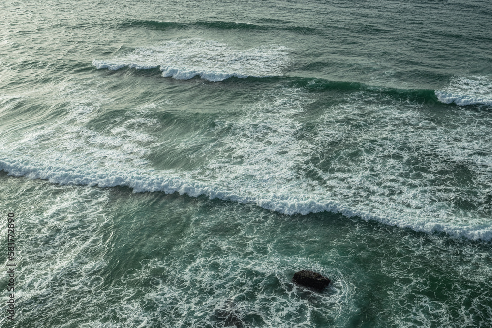 Ocean foamy waves approaching rocky shore. Top view. Ocean foamy waves approaching rocky shore. Top view.