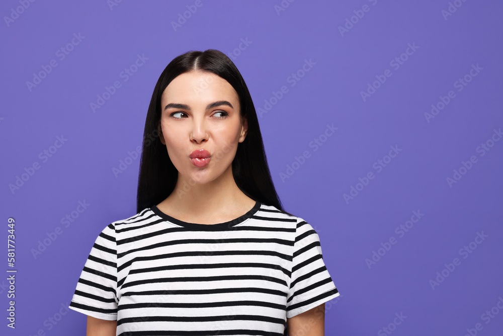 Beautiful young woman blowing kiss on purple background Beautiful young woman blowing kiss on purple background