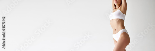 One slender young woman with sportive body shape in cotton inner wear posing over white background. Concept of natural beauty, body and skin care, sport, fitness, dieting © Lustre
