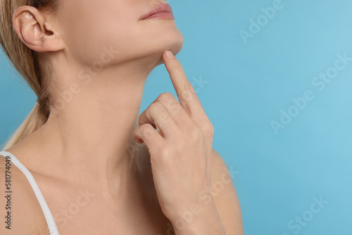 Woman massaging her face on turquoise background  closeup. Space for text