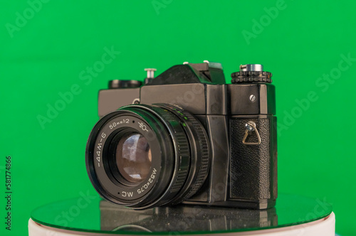 analog photo camera with lens isolated on a turning platform with green background