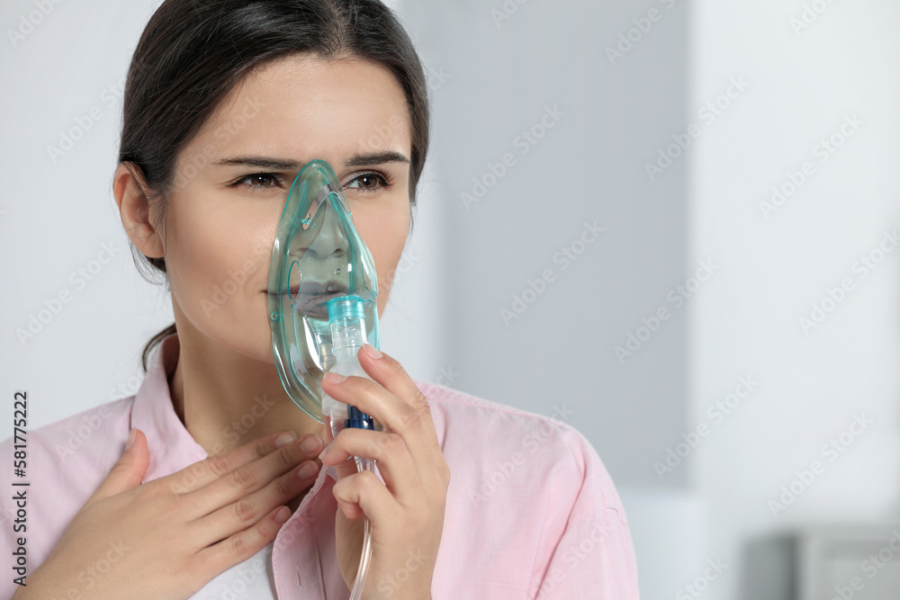 Sick young woman using nebulizer at home, space for text
