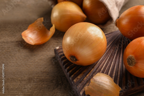 Many ripe onions on wooden table  closeup. Space for text