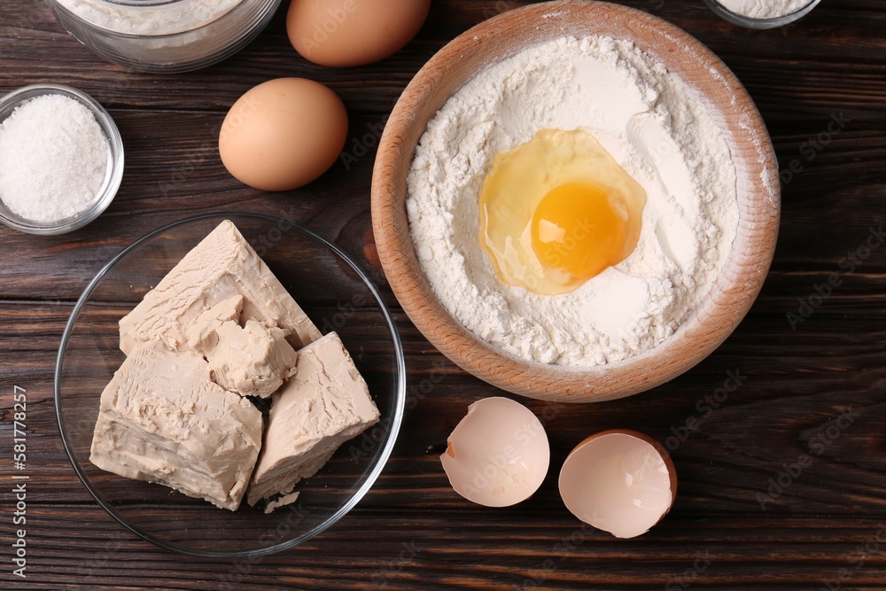 Compressed yeast, flour, salt and eggs on wooden table, flat lay Compressed yeast, flour, salt and eggs on wooden table, flat lay