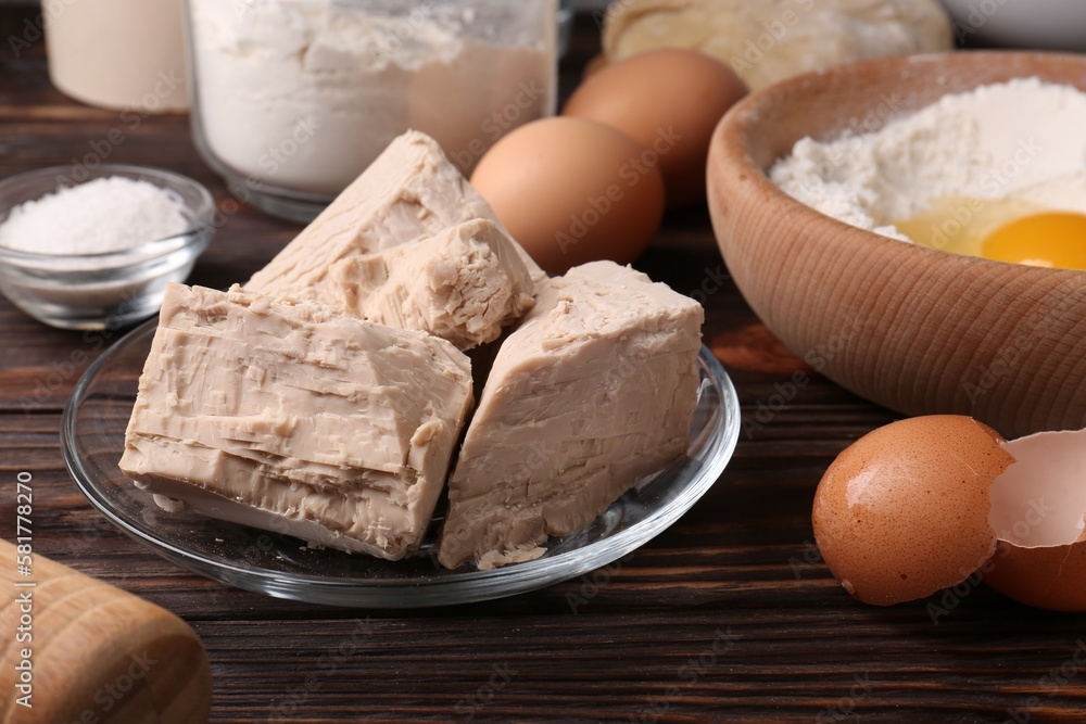 Fototapeta premium Compressed yeast, eggs, salt, dough and flour on wooden table