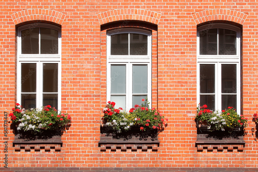 Fenster mit Blumenkästen an einer rötlichen Hausmauer aus Backstein, Wunstorf, Niedersachsen, Deutschland
