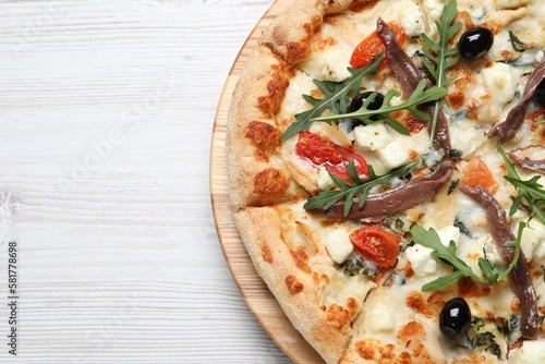 Tasty pizza with anchovies, arugula and olives on white table, top view. Space for text