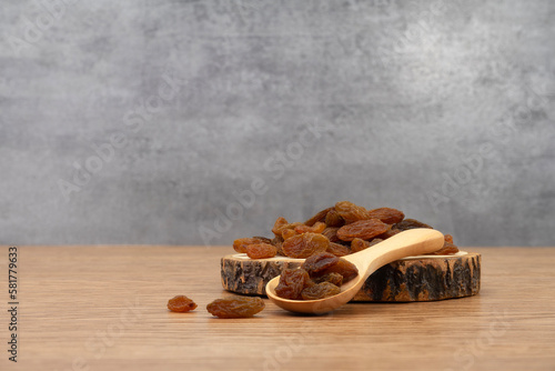 Raisins and wooden tray on wooden texture background. Dry raisins. Bulk raisins grains.