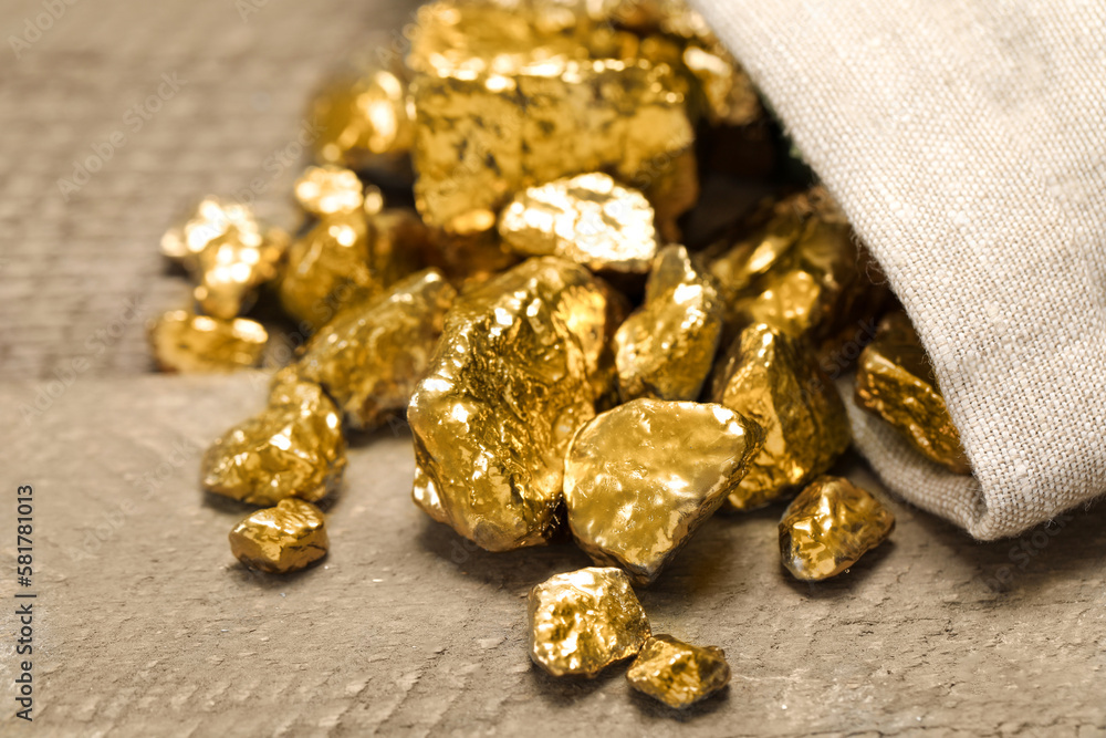 Overturned sack of gold nuggets on wooden table, closeup Overturned sack of gold nuggets on wooden table, closeup