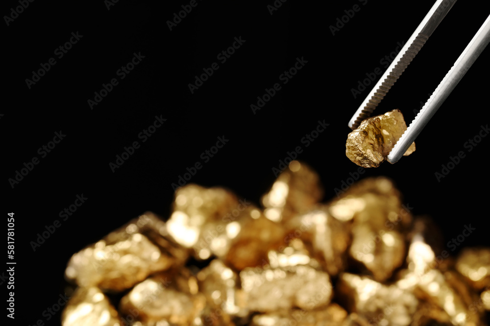 Tweezers with gold nugget against blurred background, closeup. Space for text Tweezers with gold nugget against blurred background, closeup. Space for text