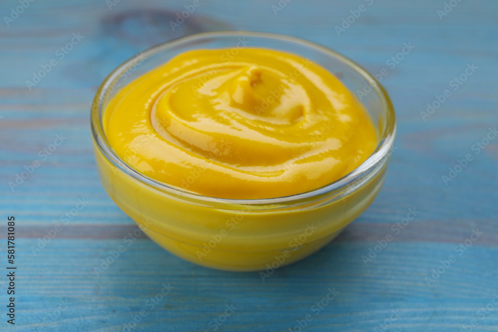 Sauce bowl with delicious mustard on light blue wooden table, closeup Sauce bowl with delicious mustard on light blue wooden table, closeup