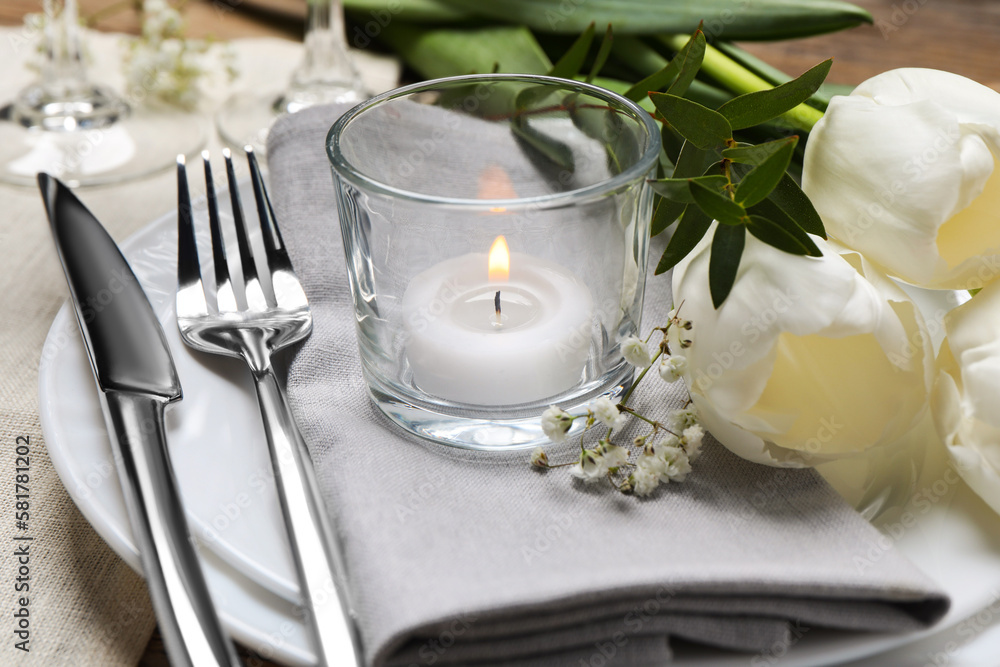 Stylish setting with cutlery, burning candle and tulips on table, closeup Stylish setting with cutlery, burning candle and tulips on table, closeup